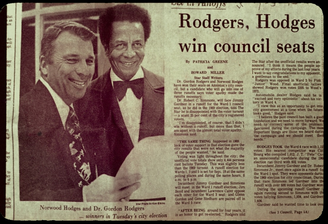 Newspaper clipping with the headline “Rodgers, Hodges win council seats” and a photograph of Norwood Hodges and a smiling Dr. Rodgers in a bow tie.